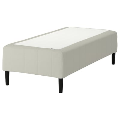 A white RÅHOLMAR mattress base. It has five comfort zones for spine alignment, black wooden legs, and a simple, modern design.