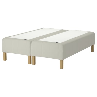 Displays an IKEA RÅHOLMAR bed frame, featuring a white upholstered base with wooden legs.
