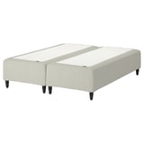 The RÅHOLMAR bed base in white with wooden legs, featuring a modern upholstered design.