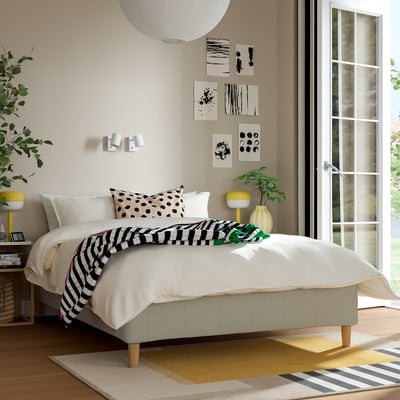 Modern bedroom with RÅHOLMAR bed, polka dot pillows, yellow nightstands, art, and green plant.
