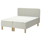 Light gray upholstered bed with wooden legs, minimalistic headboard.