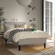 Modern bedroom with neutral RÅHOLMAR bed, stripes, and minimalist art. Bright, natural light from large window.
