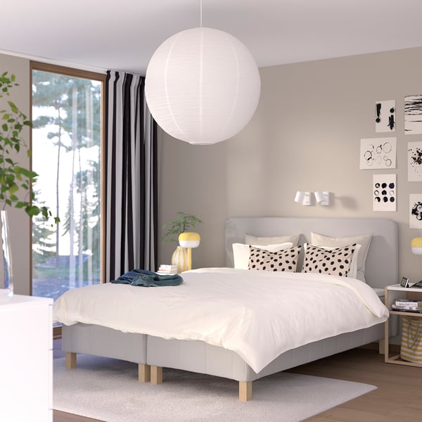 Modern bedroom with RÅHOLMAR white bed, large hanging light, black curtains, pillows with black dots, art on wall.