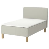 An IKEA RÅHOLMAR bed in light beige, made of fabric and wood, with a curved headboard and wooden legs.