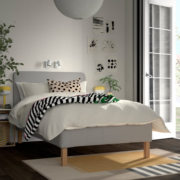 Minimalist bedroom with gray råholm bed, 5 comfort zones, black/white decor, abstract art, yellow lamp, striped rug.