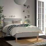 Minimalist bedroom with gray råholm bed, 5 comfort zones, black/white decor, abstract art, yellow lamp, striped rug.