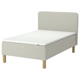 An IKEA RÅHOLMAR bed in white, featuring a padded headboard, wooden legs, and a memory foam mattress topper.