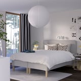 Modern bedroom with RÅHOLMAR gray bed, polka dot pillows, pendant light, nightstand, lamp, plant, window, curtains, rug.