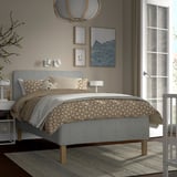 Modern bedroom with gray RÅHOLMAR bed, patterned beige bedding, gray headboard, wall art, and white nightstand.