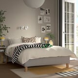 Modern bedroom with RÅHOLMAR bed, white, wooden, low; soft lighting, plants, and wall art. Bed is large, fits well in room with large window.