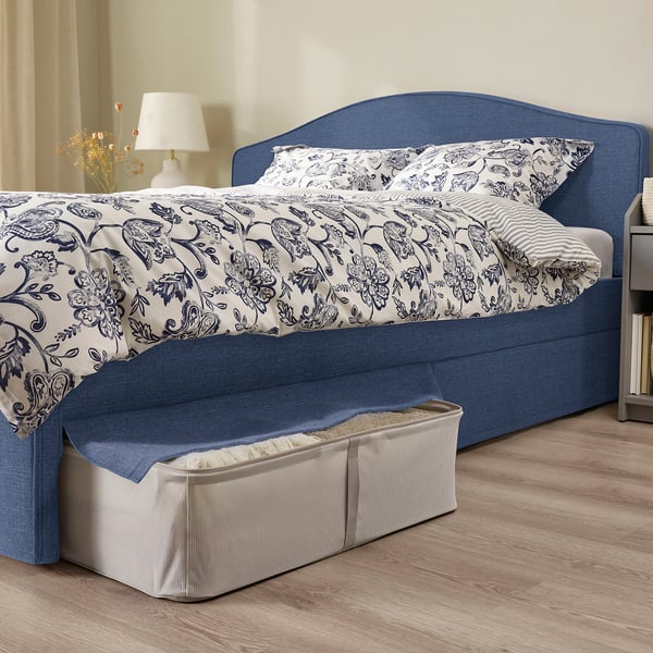 Bed with curved, padded headboard, two storage boxes under blue cover.