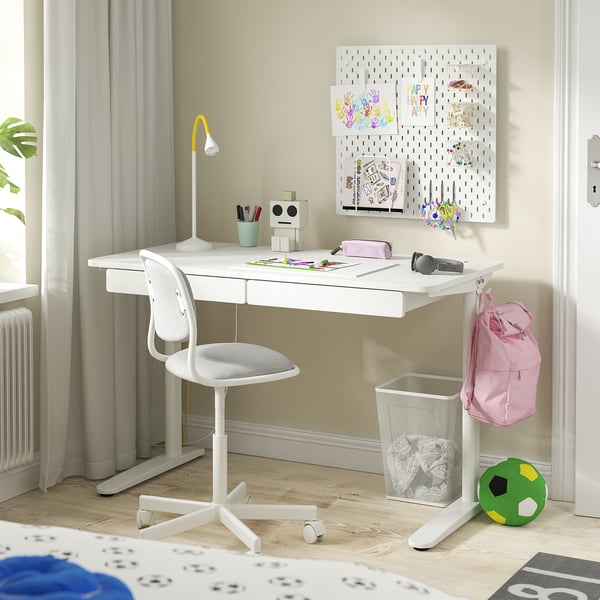 This image shows a white RELATERA desk setup with a swivel chair, lamp, drawers, and decor.