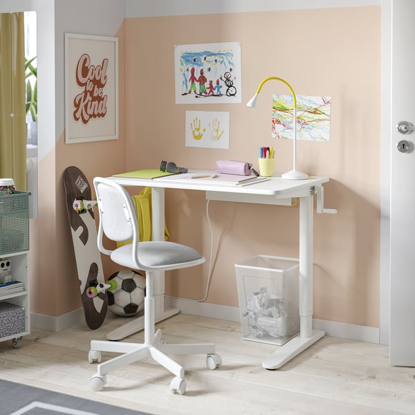 A white adjustable desk with a chair, lamp, and decorations.