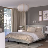 Bedroom with RENFJÄLLET grey bed, geometric bedding, hanging lamp, window with curtains, and wall art. Bed is large compared to nightstands.