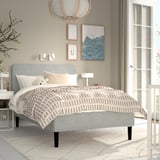 Minimalist bedroom with RENFJÄLLET bed, black legs, white headboard, chequered blanket, lights, art, side lamp, large window, off-white rug.