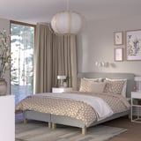 Modern grey RENFJÄLLET bed with geometric bedding, pendant light, nightstands, floral art, and large windows.