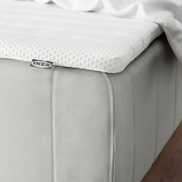 Black and white a white mattress with textured topper, small black label with IKEA visible on corner.