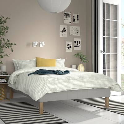 Bedroom with RENFJÄLLET bed, white grid cover, yellow pillow, black/white rug, art, plant, large window.