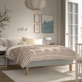 A cozy bedroom with a RENFJÄLLET bed, white and beige striped bedspread, and three hanging lamps. Art above bed, left nightstand, right window.