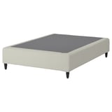 RENFJÄLLET bed base. Cream-colored, upholstered rectangular platform with grey top. Four black legs.