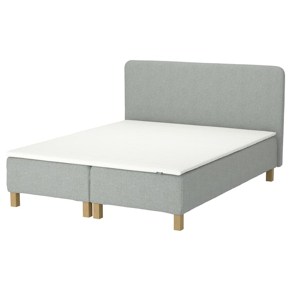 Alleviating; light grey bed with wooden legs and a padded headboard.