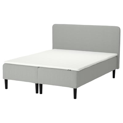 Minimalist bed in light grey fabric with black legs and foam mattress.