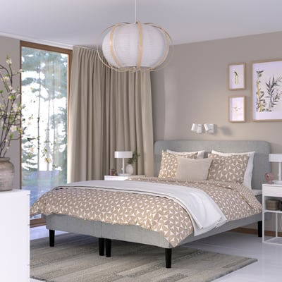 Minimalist bedroom with bed, neutral linens, pendant light, sliding door to greenery, art, and bedside table.