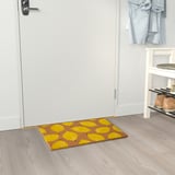 Bright yellow lemon-patterned door mat at entrance, welcomes guests, made of eco-friendly coir.