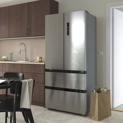 Large stainless steel refrigerator, tall, silver, four doors, in kitchen, next to counter.