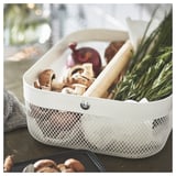 White RISATORP storage bin with mesh design, containing mushrooms, onion, and herbs, has a handle for easy transport.