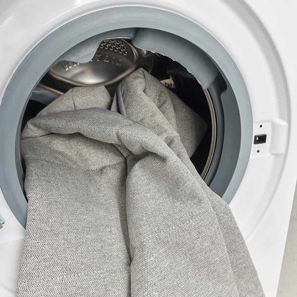 Washing machine drum with gray blanket and metallic component.