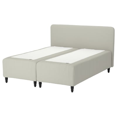 The RISHÖJDEN bed, off-white, a padded headboard and footboard with sturdy black legs, providing a cozy and stylish look.