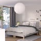 Modern bed, white headboard, dotty spread, black curtains, large pendant light, under window.