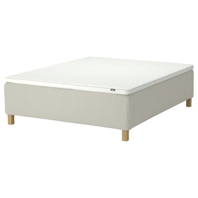 The RISHÖJDEN bed base in white. It has a modern design with upholstered sides and wooden legs, creating a cosy and minimalist look.