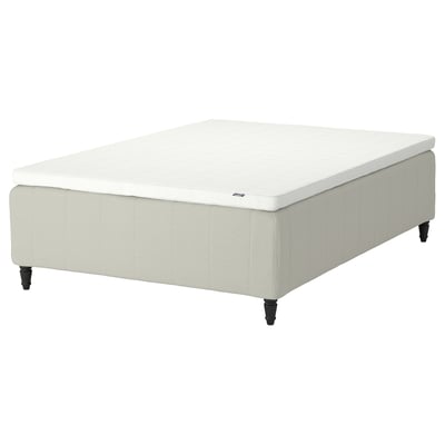 A RISHÖJDEN mattress in beige with wooden legs and a 7-zone pocket spring core. It has a padded base and comes with a removable cover.