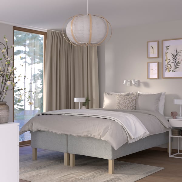 Modern bedroom: gray bed, white linens, hanging light, large window, side tables, rug.