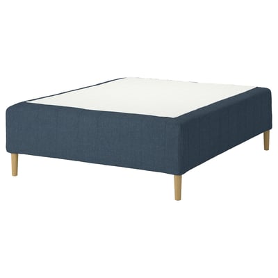 A RISHÖJDEN bed base in blue with wooden legs. It a modern upholstered design with a white mattress on top.