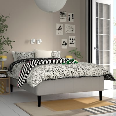 Modern bedroom with RISHÖJDEN bed, black & white bedding, plants, and stylish decor.