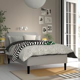 Modern grey RISHÖJDEN bed with black/white bedding and wall art.