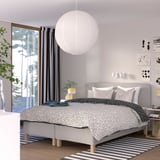 Modern bedroom with RISHÖJDEN bed, grey & white decor, spherical light.