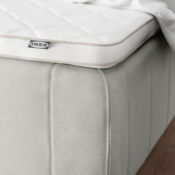 Close-up of a firm, white IKEA mattress with quilted top, featuring reinforced edges for safety and comfort.