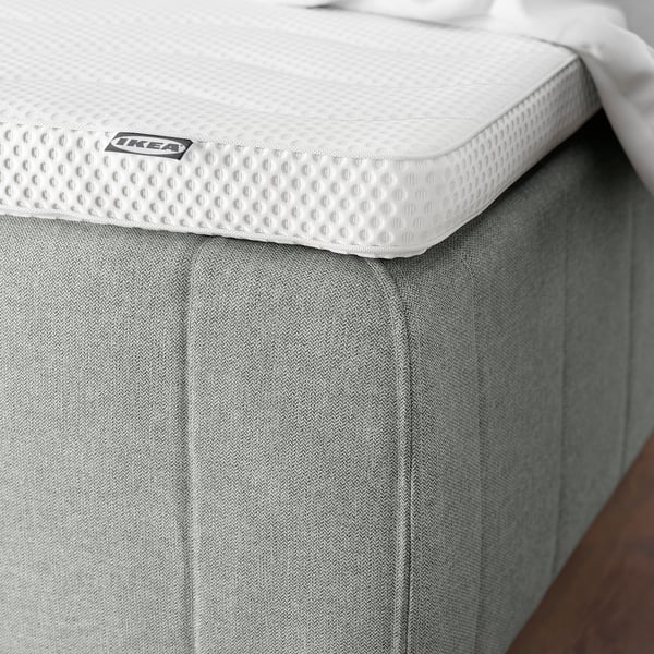 Close-up of a mattress with reinforced edges and a soft headboard, designed to prevent sliding and provide comfort.