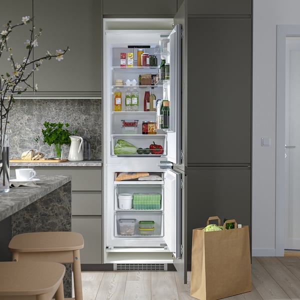 Open fridge/freezer combo with adjustable shelves, showing groceries and produce inside.