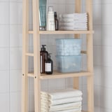 Wooden bathroom shelf with blue boxes and towels. Holds toiletries and organizes items.