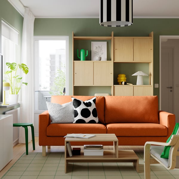 Orange SALTSJÖBADEN sofa in cosy living room, minimalist design, green chair, natural light, striped light.