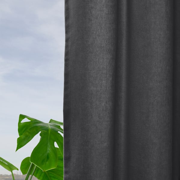 Dark grey curtains hang near a green plant, filtering soft light.
