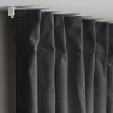 Black velvet curtains hang with pleated folds, closed and room-darkening. White curtain hooks are visible at the top.
