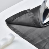 Gray velvet curtains being ironed, showing room-darkening fabric and pleated design.