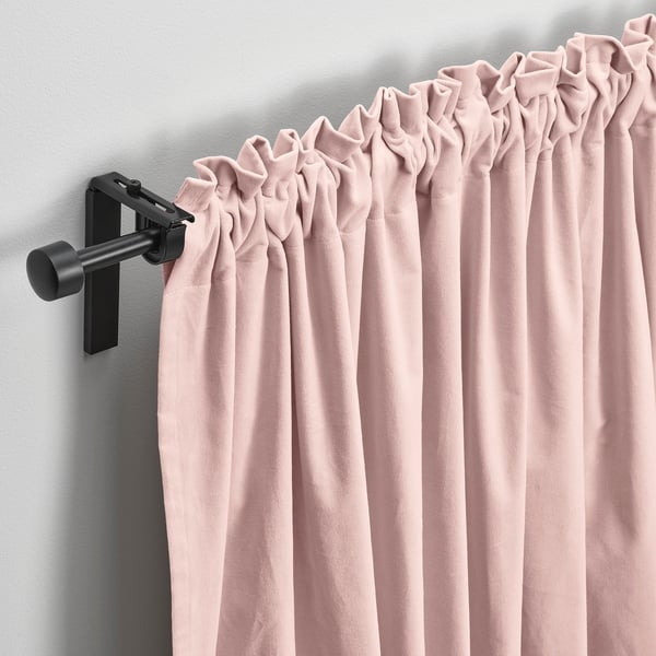Blush pink velvet curtains hang on modern black rod, gently pleated, filtering light, offering privacy and warmth.