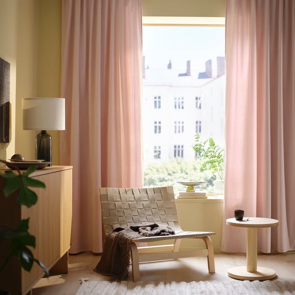 Bright room with pale pink SANELA curtains, a wicker chair, and minimalist decor, offering a cozy, stylish atmosphere.